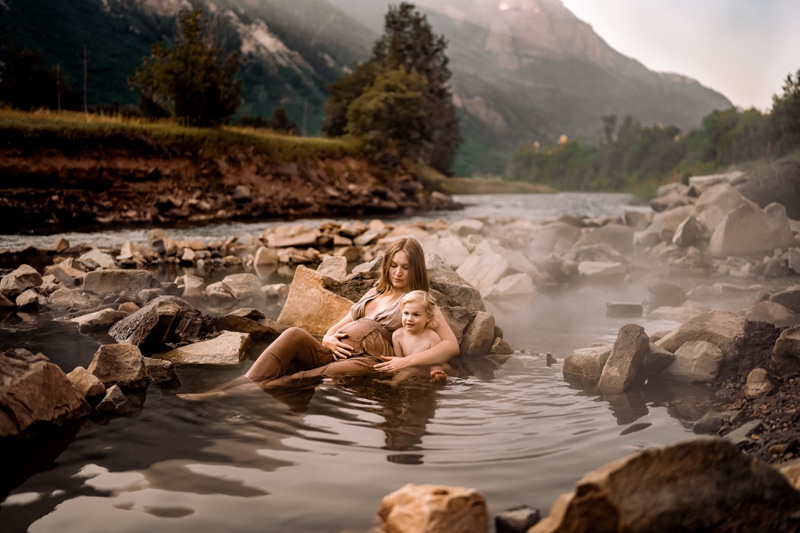Salty Preset Pack, a pregnant mother holds her young toddler as they sit in quiet hot springs in the mountains