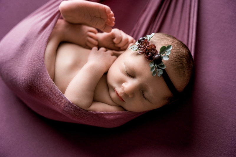 Salty/Moor Preset Pack, lightened and edited images, a baby lays sleeping swaddled in blankets, she wears a little floral headband