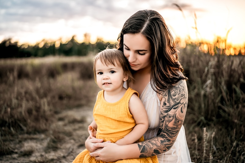 Salty Preset Pack, a mother holds her baby on a path through tall grass, mom wears a sleeveless dress and has a tattoo sleeve on her arm
