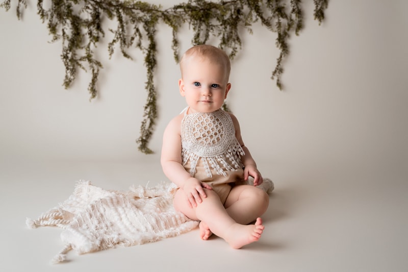 Moor Preset Pack, a baby girl wears woven clothing in a studio, forest green plants behind her