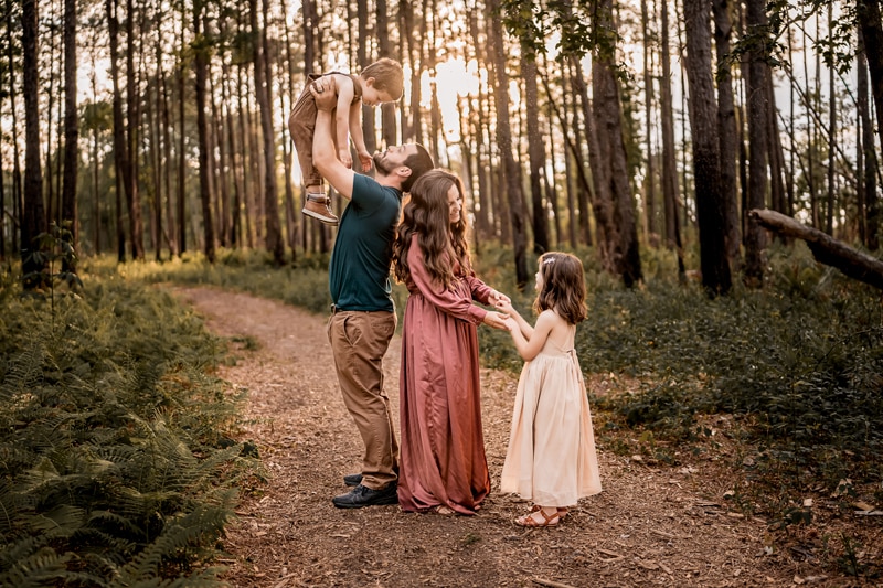 Salty Preset Pack, Lightened and edited image, dad lifts young son in the air, mom holds daughter's hands, they are in the forest